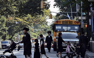 In this Sept. 20, 2013 file photo, children and adults cross a street in front of a school bus in Borough Park, a neighborhood in the Brooklyn borough of New York that is home to many ultra-Orthodox Jewish families. (AP/Bebeto Matthews)