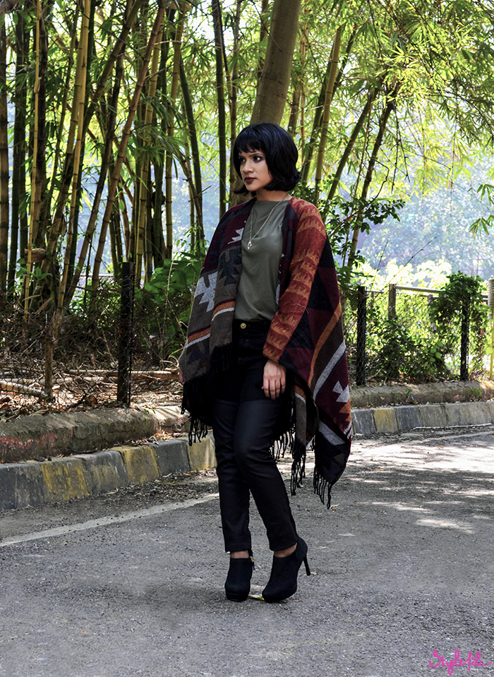 Image of fashion blogger Dayle Pereira wearing a navajo print poncho coat, leather panel black jeans, black booties, plum copper eye makeup and a dark brown lip