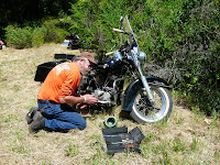 A man working on Harley Panhead Motorcycle while camping