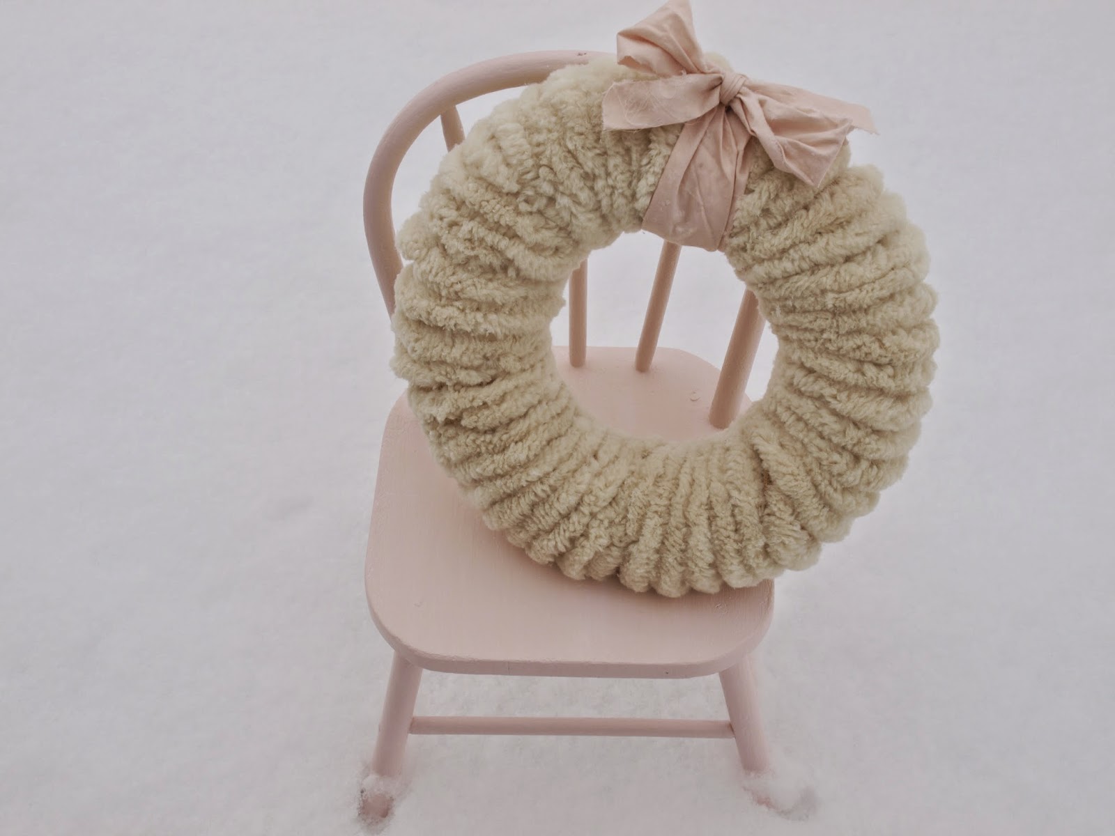 Hello Lovely Studio wooly pom pom Christmas wreath on pink chair in snow