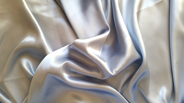 a swathe of pale blue-grey shiny satin fabric.