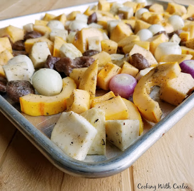 chopped vegetables coated in seasoning and spread over baking tray ready to go in oven to roast