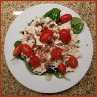 Pasta & green salad with tomatoes in a white bowl on a counter