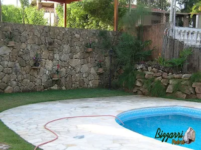 Construção de piscina em residência em Mairiporã-SP com o muro de pedra, o piso com pedra caco de São Tomé e a execução do gramado com grama esmeralda.