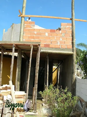 Detalhe da laje em cima das vigas de madeira apoiadas nos pilares de madeira de eucalipto tratado com a alvenaria de tijolo baiano em cima das vigas de madeira e fixado nos pilares de madeira em ampliação da casa com a sala de estar e a suíte superior.