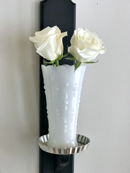 White roses in milk glass on candlestick base
