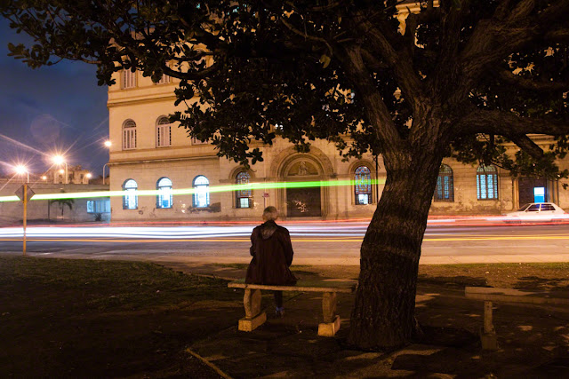 Havana, Cuba a man watching traffic go by at night by Marlon Krieger