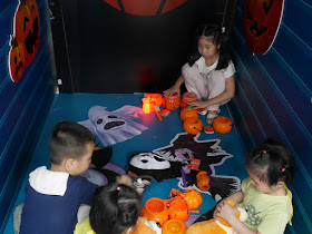 children playing with toys inside a display of Halloween items for sale at an RT-Mart in Zhongshan