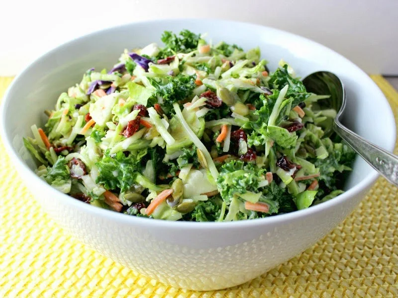  Broccoli, Kale, and Brussels Sprouts Slaw in white bowl, angle view with spoon