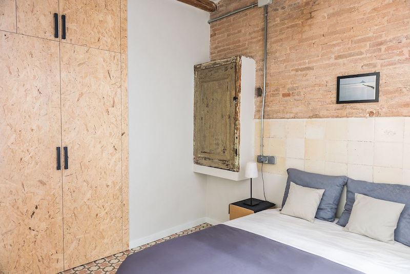 Apartamento con muebles de cartón y la instalación vista Dormitorio con armario de puertas de madera de OSB y suelo hidráulico