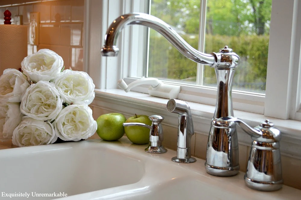 Pfister Marielle faucet on white kitchen sink with white roses near it