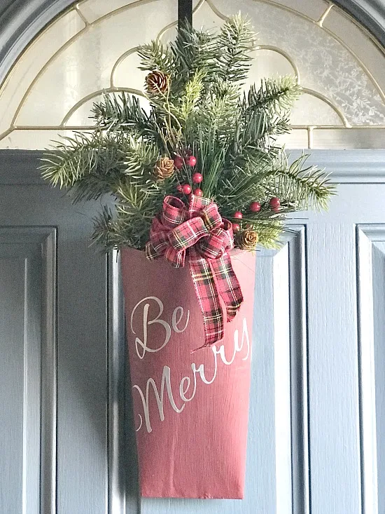 Repurposed door bouquet for the holidays using greens and a vinyl sign