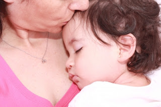 Bebé dormido en brazos de mamá