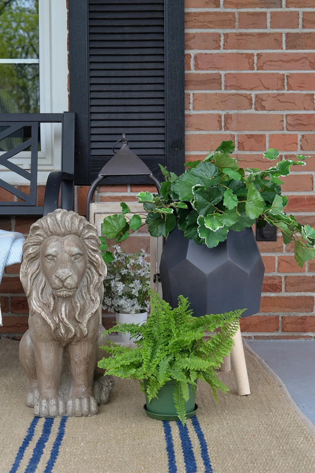 front porch decorated with artificial outdoor plants, outdoor lantern, lion garden statue, geometric planter