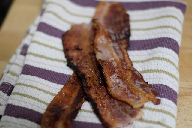 The three pieces of bacon, fully cooked, on a towel.  