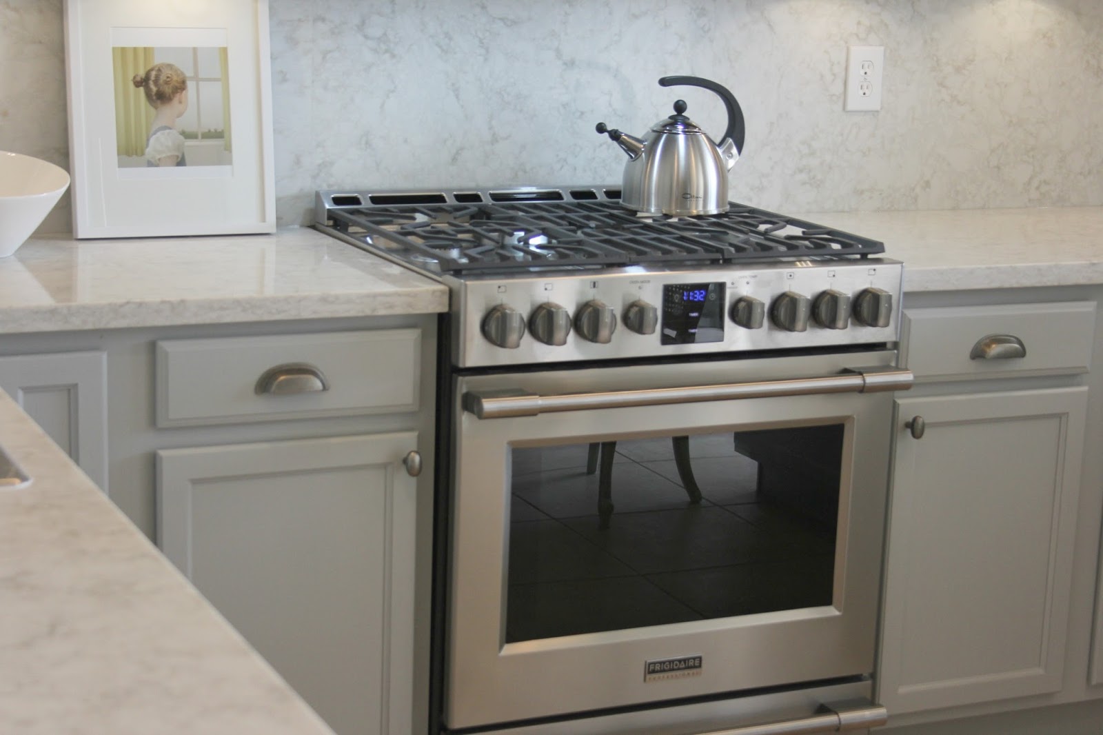 Modern farmhouse kitchen with grey cabinets, cup pulls, and quartz