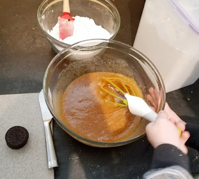 kid's hand stirring bowl of blondie batter with whisk