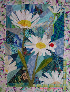 Art quilt of a ladybug on daisies. Bright red ladybug rests on the white petal of a daisy in this original art quilt.