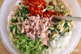 Ingredients for creamy tuna pasta salad in bowl with spoon ready to be mixed