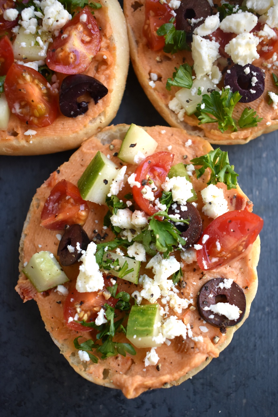 Mediterranean Hummus Bites are loaded with red pepper hummus, kalamata olives, tomatoes, cucumber and feta cheese on a toasted English muffin for an easy appetizer ready in 10 minutes that everyone will love! www.nutritionistreviews.com #healthy #appetizer #cleaneating #holidays