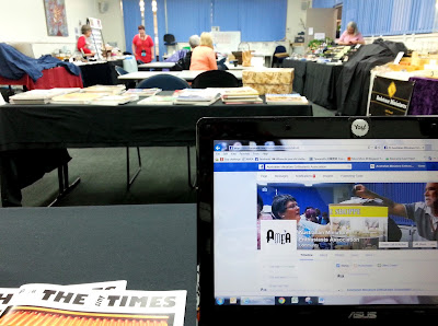 View of a doll's house show sales room from behind a laptop at one of the tables.