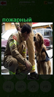  около дерева мужчина пожарный сидит вместе с своей собакой