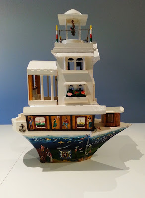 Miniature wooden painted artist's arks on display in a gallery.