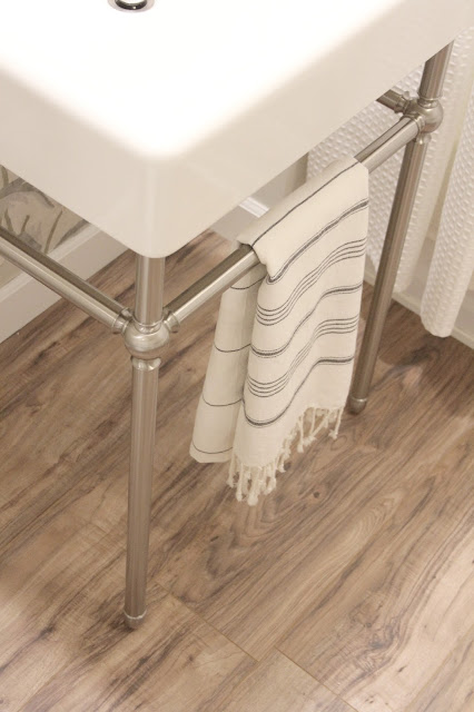 Brushed nickel legs on DXV's Oak Hill console sink in a timeless classic bathroom by Hello Lovely Studio.