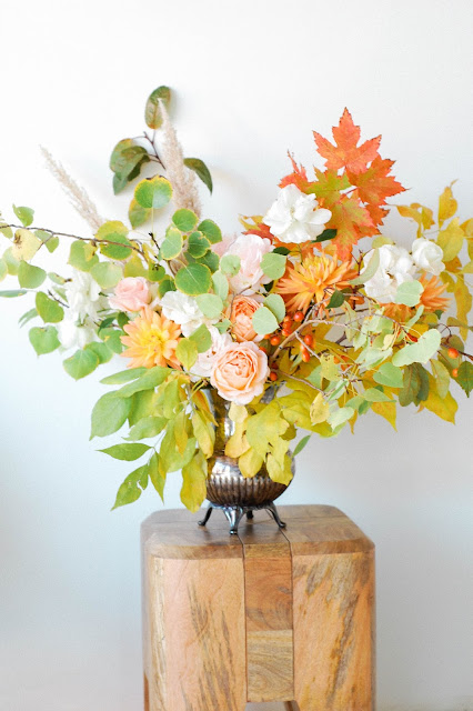 foraged fall aspen and maple branches with peach and white garden roses, dahlias, berries and grasses arranged in an antique silver pitcher