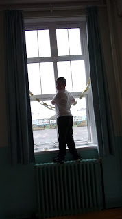 hanging party paper chains in window schoolboy standing on radiator in assembly hall