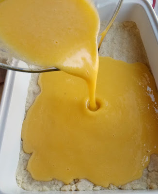 pouring lemon filling over shortbread crust for lemon bars