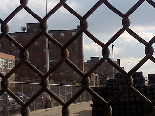 View of a Chicago Housing Development thru a chain linked fence symbolizing oppression