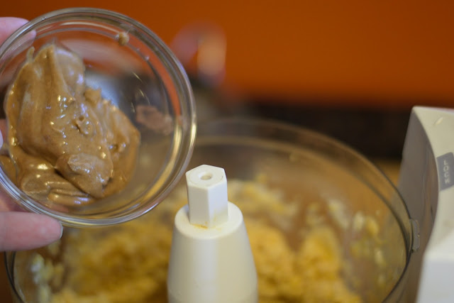 Almond butter being added to the food processor. 