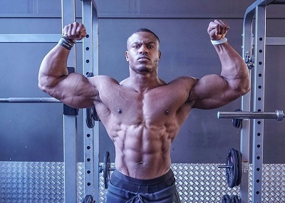 Acelerar la recuperación muscular Hombre muy musculado sin camiseta posando en el gimnasio
