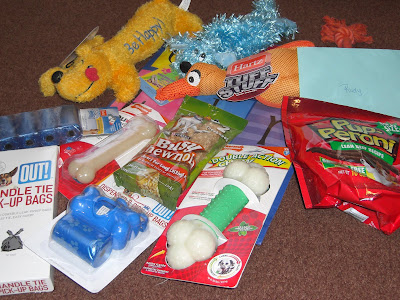 Picture of all the toys and such The Hound Dog's sent us... including stuffies, dog treats, clean up bags, and nylabones