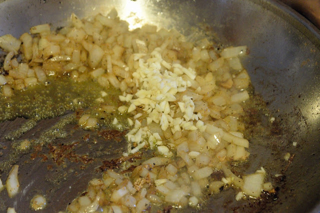 Minced garlic  in the skillet with diced onions, in the skillet on the stove. 