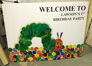 Welcome to Lawson's 1st Birthday Party colourful hungry caterpillar sign printed on vinyl and mounted on correx.