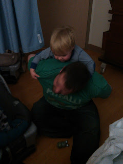 Man sitting on floor with toddler son climbing on him