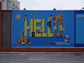 Wanda Plaza "Hello" sign on a wall bordering a construction site in Mudanjiang, China