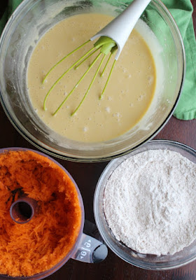 bowls of wet and dry ingredients for carrot cake and food processor with shredded carrots