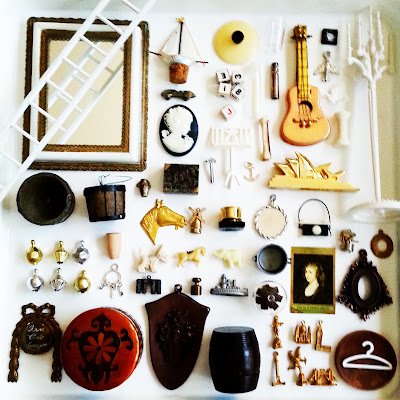 Flatlay of vintage dolls' house miniatures in gold, silver, white, black and brown colours.