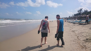 Two tourists walk on a beach in Hoian, Vietnam
