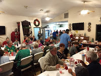 Christmas potluck people sitting at long tables eating food and talking