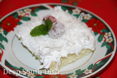 Tender, homemade coconut cake made easy in a sheet cake, finished with a 7-minute, divinity icing, shredded coconut and here, with a sugared cranberry and mint leaf garnish.