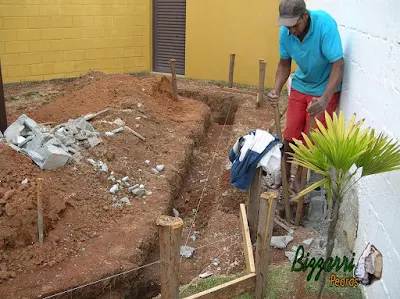 Já com o gabarito da obra marcado, iniciando a abertura das valas com a sapata corrida e executando os buracos para chumbar os pilares de madeira com eucalipto tratado.