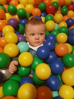 baby in ball pit surrounded by colourful balls 