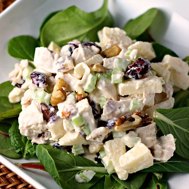 Waldorf Style Chicken Salad on white plate with spinach