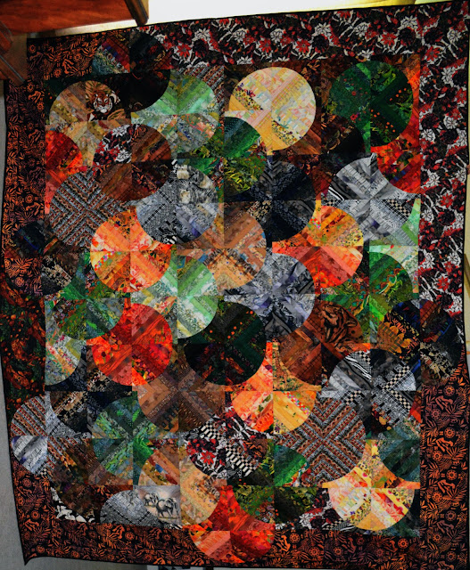 Queen sized Strips and Curves quilt One-inch fabric strips in orange, yellow, green brown, black & white create this Drunkard's Path variation.