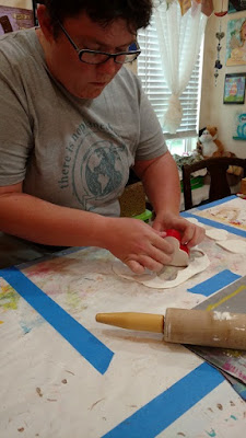 Julia using a heart-shaped cookie cutter to cut out the clay shapes
