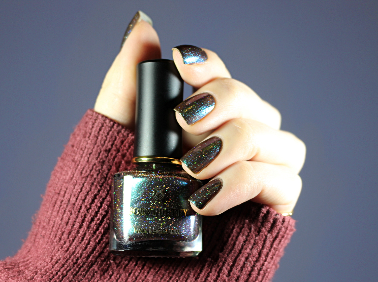 a close-up of a green holographic nail polish bottle by born pretty